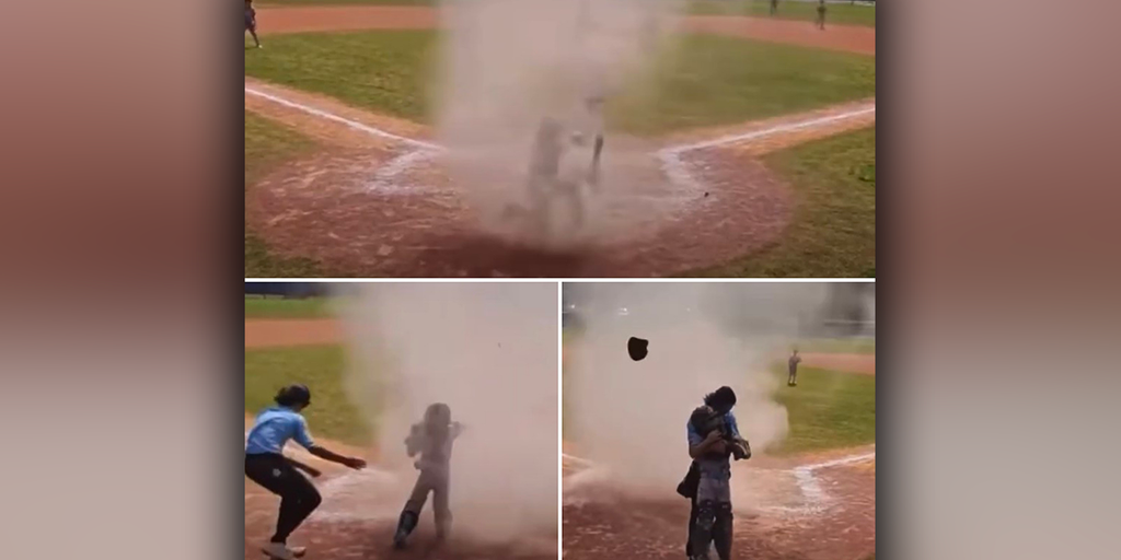 Featured image for Umpire rescues young catcher from dust devil during baseball game.
